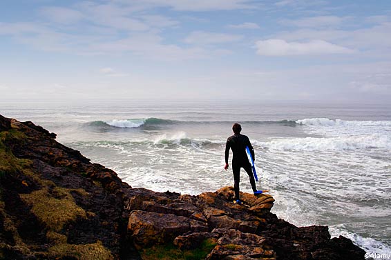 A surfer looks at waves at Tullan Strand, County Donegal, Ireland
